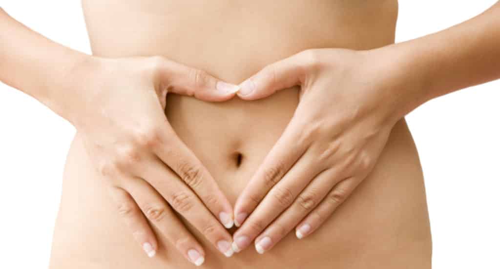 Two hands forming a heart shape over a bare abdomen