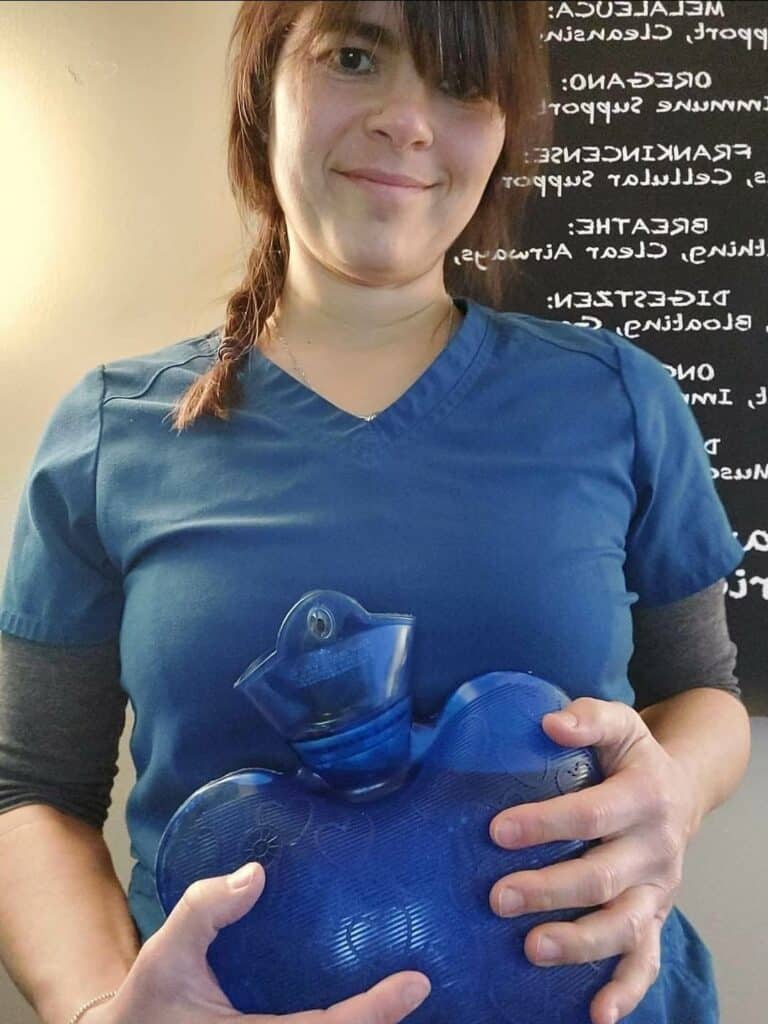 Briana holding a blue hot water bottle against her abdomen